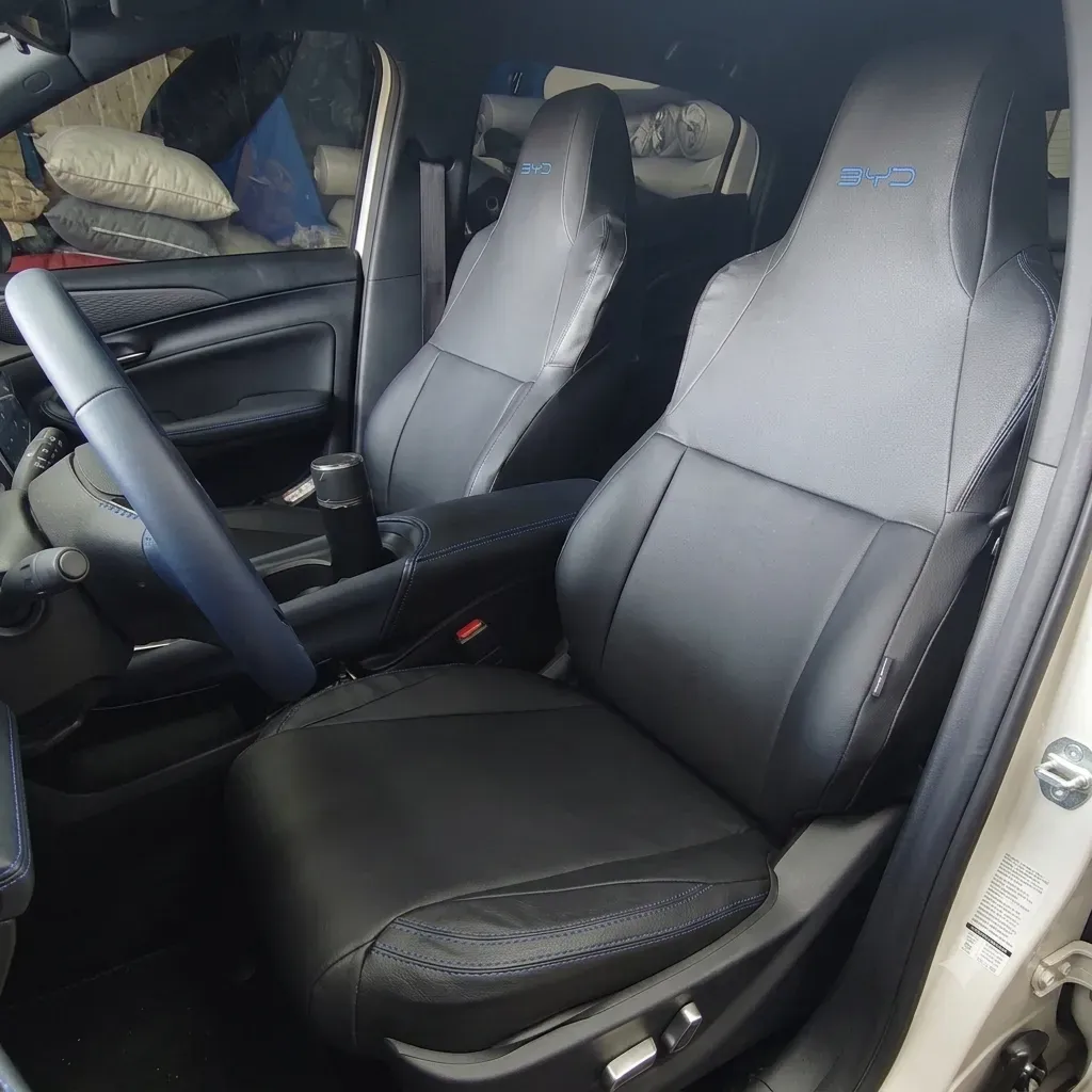 Capa de banco de couro sintético preto sob medida instalada no BYD Dolphin Mini, com bordado BYD no apoio de cabeça