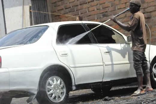 Pessoa lavando um carro à mão com espuma e luva de lavagem