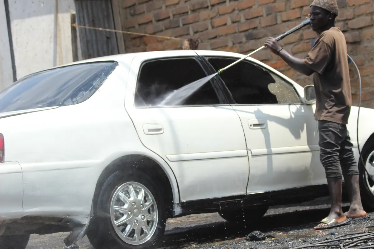 Pessoa lavando um carro à mão com espuma e luva de lavagem