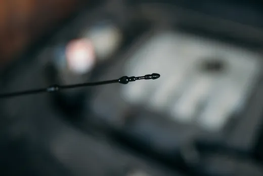 Pessoa verificando o nível de óleo do motor de um carro pela vareta